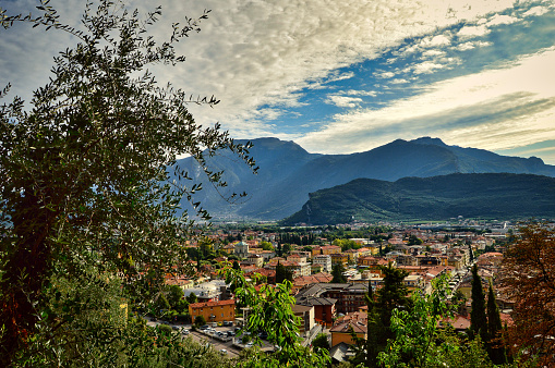 landscape photo of the beautiful morning view from above to town Riva del Garda, mountains, buildings, lake Garda, Monte Brione, blue cloudy sky