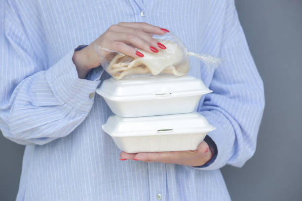 istock Woman's hands holding takeaway foam lunch boxes. Single use food containers, close up. 1463751220