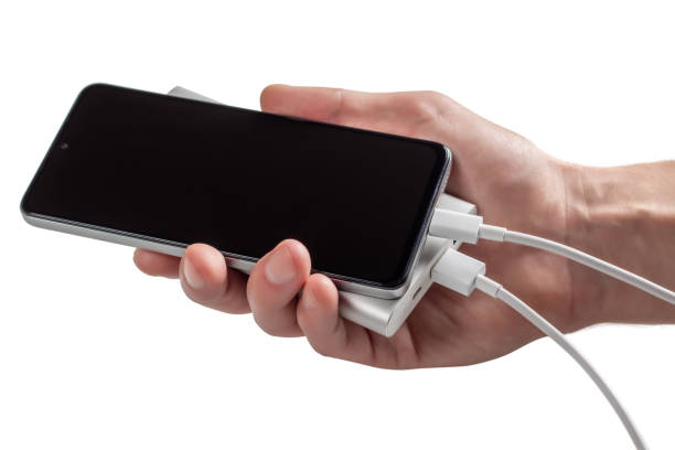 istock Hand holding smartphone with powerbank. Isolated on white. 1463754247