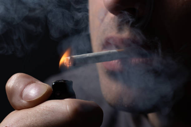 istock Man smoking a cigarette on black background. close up 1463754663