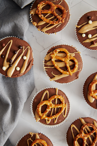 A vertical closeup of delicious no-bake muffins with sweet-salty chocolate on a white table.