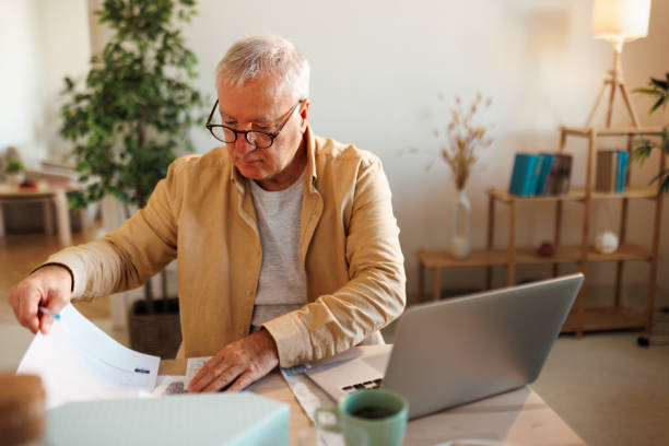 istock Concentrated senior man going over paperwork at his apartment 1463756553