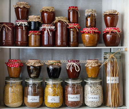 Glass jars of homemade jam and glass containers with herbs, pasta and beans