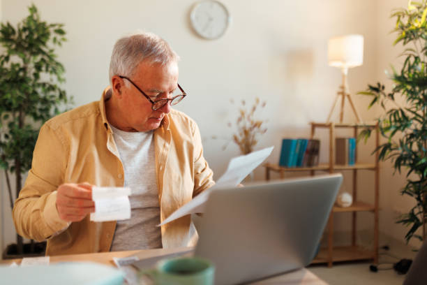 istock Concentrated senior man going over paperwork at his apartment 1463756674