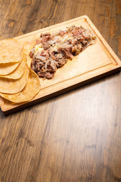 Vertical shot of cooked chopped meat with onions on a wooden board