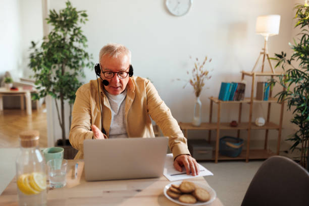 istock Senior man with headset having video call at his apartment 1463757099