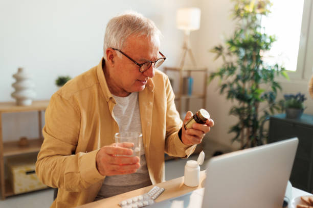 istock Senior man holding pill container while having online meeting with doctor 1463758800