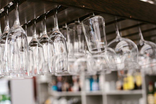 Many glass cups hanging on a shelf to dry