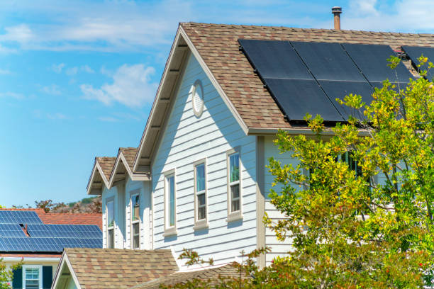 Sunny day in a rural town with solar panels on brown tile roofs under a bright blue cloudy sky