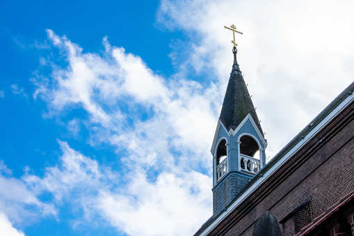 A low angle shot of a church steeple against a cloudy blue sky