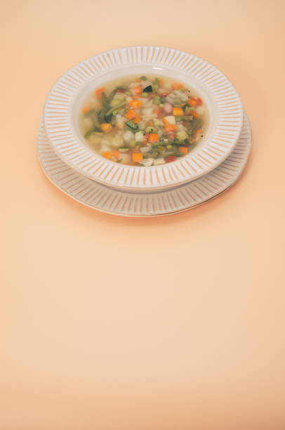 istock Vertical shot of vegetable soup on a bowl isolated on light orange background 1463766268