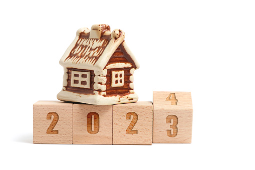 Wooden cubes with inscription 2023 turning into 2024 and house on white background