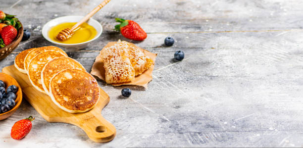 istock Homemade pancakes on a cutting board with honey and berries. 1463768012