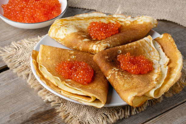 istock Stack of russian thin pancakes blini with red caviar on an old wooden table. Maslenitsa, traditional Russian blini 1463768317