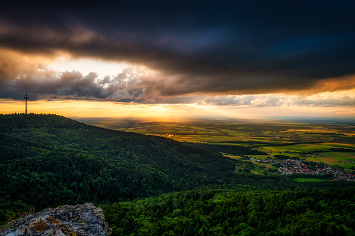 A scenic view of a vast forest landscape under a gloomy sunset sky