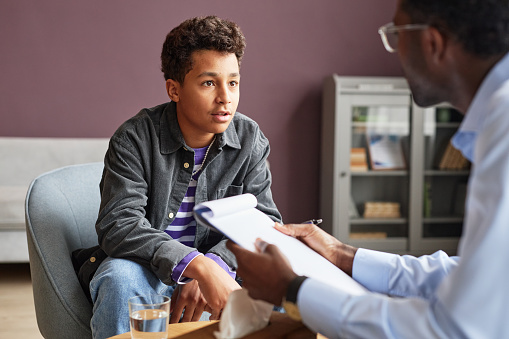 Excited teenage boy sharing his thoughts with adolescent psychologist