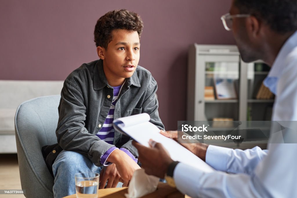 Excited Boy Talking to Psychologist Excited teenage boy sharing his thoughts with adolescent psychologist Teenager Stock Photo