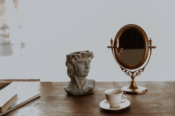 istock on an old table there is a clay figure, a vintage mirror and a book 1463775490