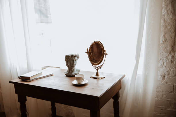 istock on an old table there is a clay figure, a vintage mirror and a book 1463775525
