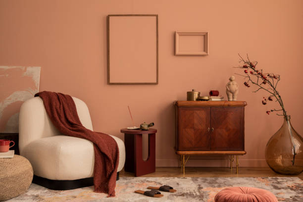 istock Creative composition of living room interior with mock up poster frame, wooden sideboard, beige armchair, plaid, vase with rowan, rug, round coffee table and personal accessories. Home decor. Template 1463775607