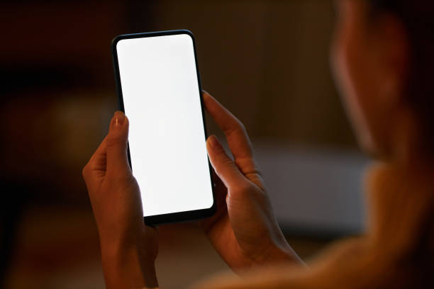 istock Closeup woman holding smartphone with white screen in dark home 1463776417