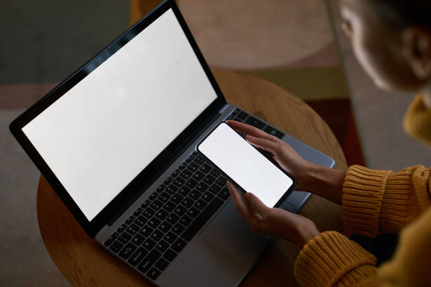 istock view at young woman using laptop and phone with blank screen mockups 1463776457