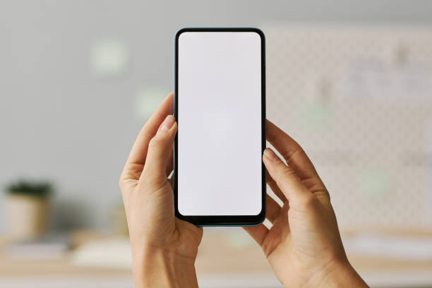 istock Female hands holding smartphone with white screen mock up 1463776990