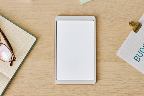 istock Minimal top view digital tablet with white screen mockup at light wood desk 1463777017