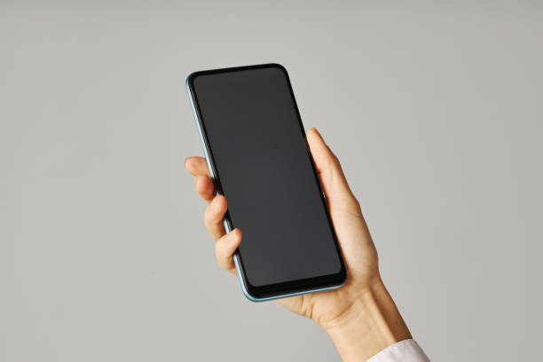 istock Minimalistic closeup female hand holding smartphone against white background 1463777549