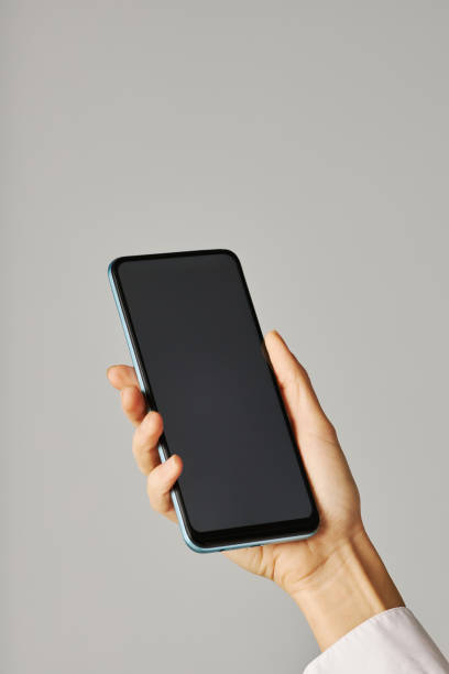 istock Vertical closeup female hand holding smartphone against white background 1463777555