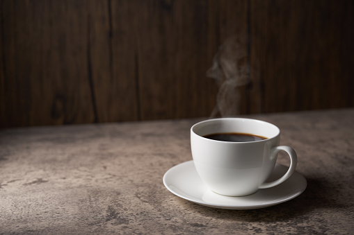 Cup of coffee with grains on wooden background