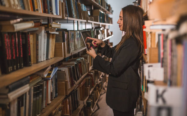 istock Side view of a librarian searches books in the library using a digital tablet 1463780923