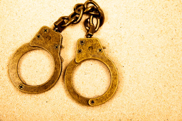 istock image of handcuffs sand background 1463781181