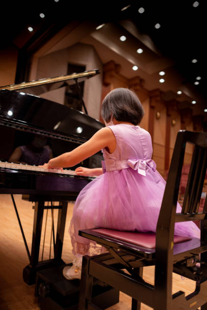 Little girl playing the piano in concert hall Little girl playing the piano in concert hall girl playing piano stock pictures, royalty-free photos & images