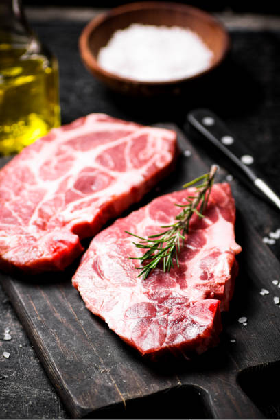 istock Raw pork steak on a cutting board with rosemary. 1463787208