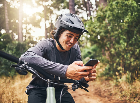 Cycling man in forest, phone gps and map direction with adventure, nature trail and bicycle break in woods. Happy mountain bike sports athlete, mobile app search and typing location guide connection