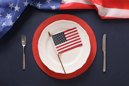 Patriotic table setting with USA flag and decoration on blue background. Independence Day. Happy Memorial Day. Top view.