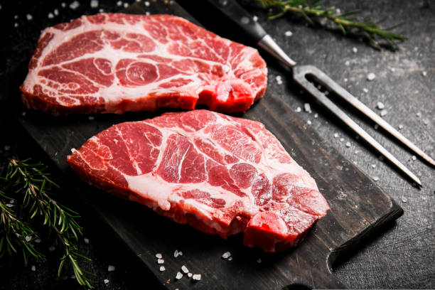 istock Raw pork steak on a cutting board with rosemary. 1463787327