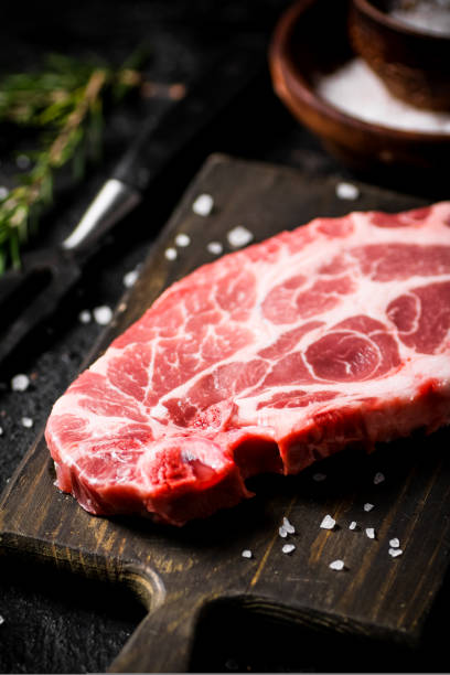 istock Raw pork steak on a cutting board with spices and rosemary. 1463788313