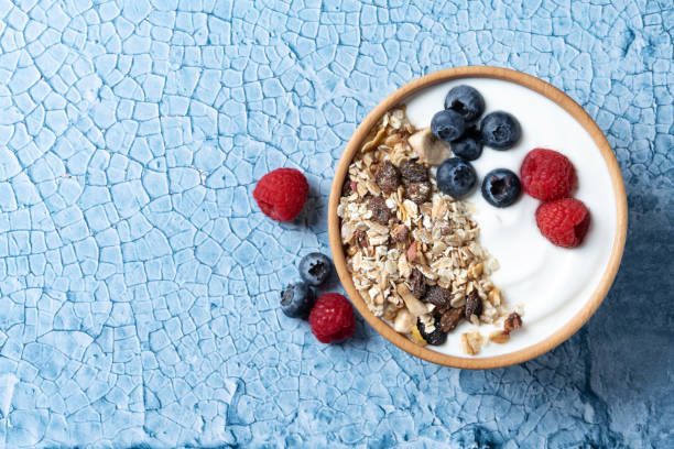 istock Yogurt with berries and muesli for breakfast in bowl on lbue background 1463790991