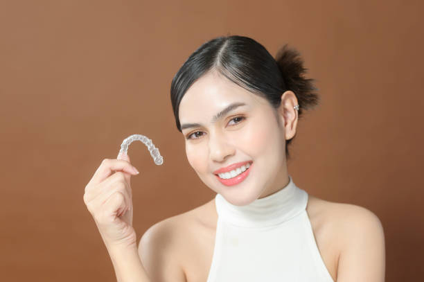 A young woman with beautiful teeth is holding Invisalign, healthy dental concept stock photo