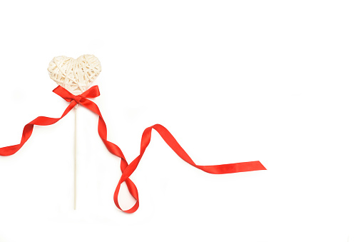 White paper heart with a red ribbon bow tie on white background with copy space