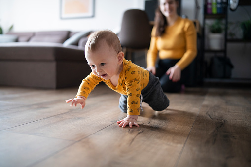 Little cute baby boy just learned to ceawl with his mommy.