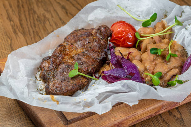 istock baked meat with vegetables and beans in white paper on a board 1463801827