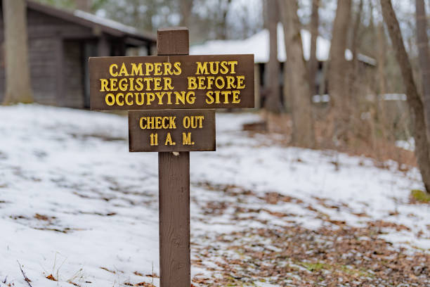 Weathered wood sign on building, Campers must register before occupying site - Check Out 11 AM.