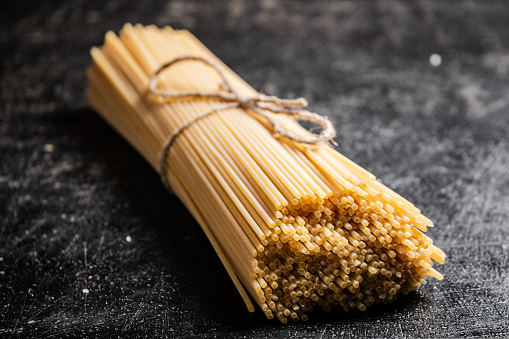 A bunch of spaghetti dry on the table. On a black background. High quality photo