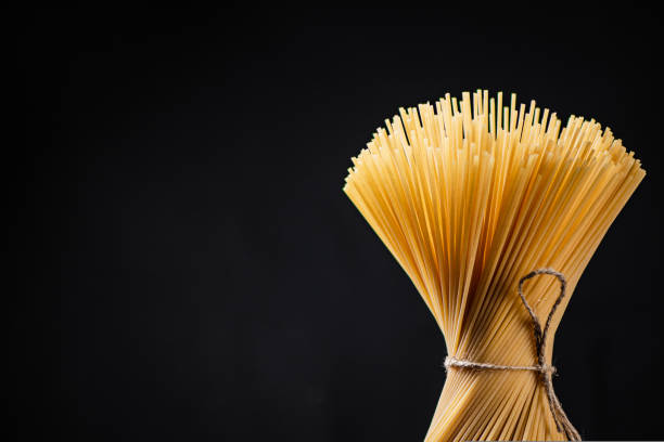 istock A bundle of spaghetti dry tied with a rope stands on the table. 1463808229