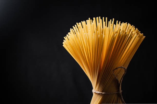 istock A bundle of spaghetti dry tied with a rope stands on the table. 1463808385
