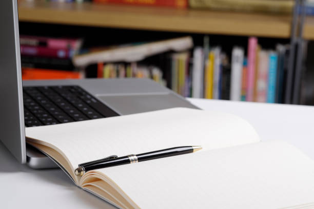 istock Close up of open note pad and  laptop computer at the library 1463812904