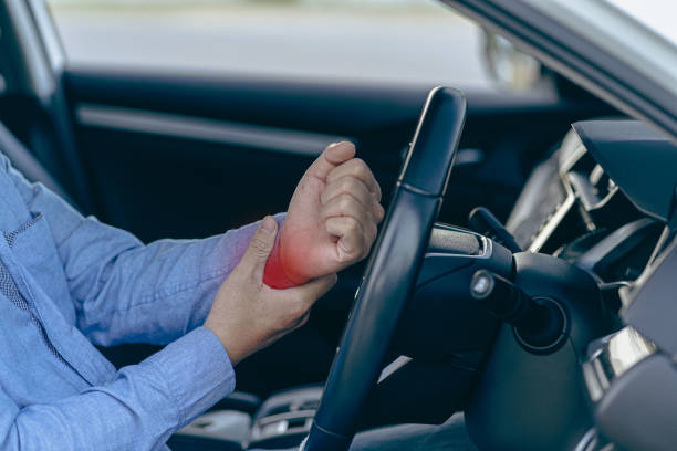 istock Man hurts wrist while driving The left hand with the red dot grasps the right wrist while holding the steering wheel. The concept of injury, pain or fatigue from driving. 1463813293
